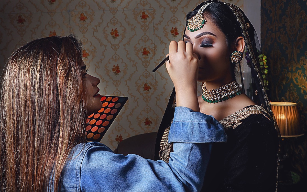 A makeup artist applying eye makeup to a model