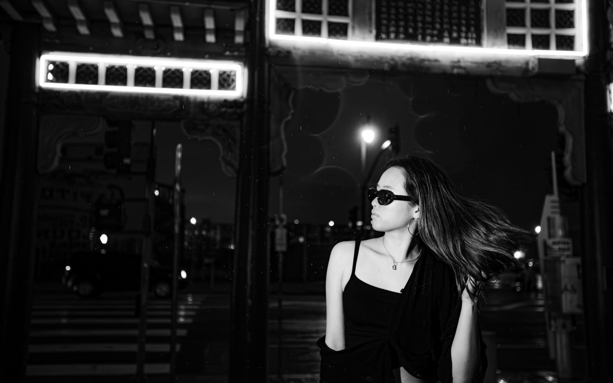 A woman beneath bright city lights at night